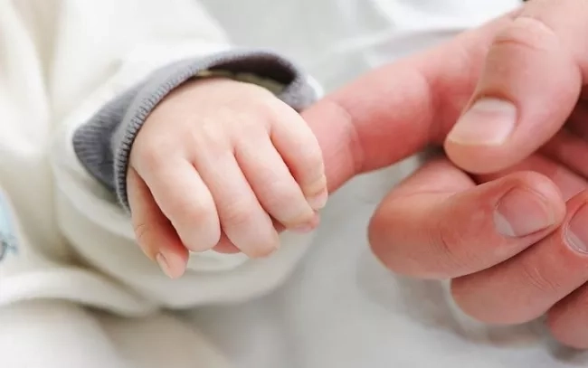 Mother holding the fingers of her newborn baby.